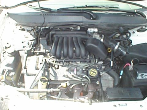 1999 Ford Taurus - Engine bay of a 1999 Ford Taurus, showing the V6 engine and battery components.