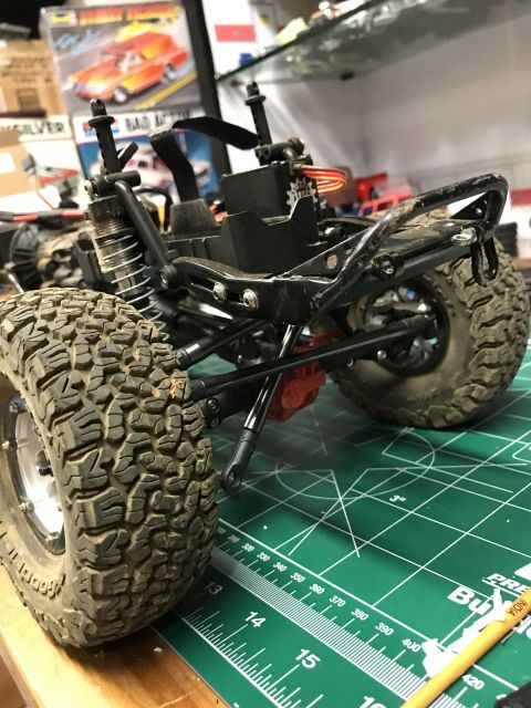 1989 Ford Bronco - Close-up of an RC car chassis and tires on a cutting mat, with model boxes in the background.