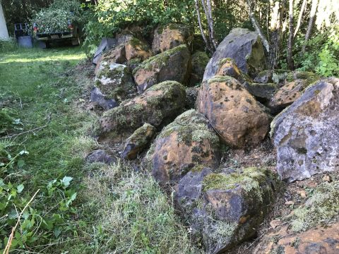 1989 Ford Bronco - A collection of large, weathered rocks covered in moss sits on the ground next to a grassy area.