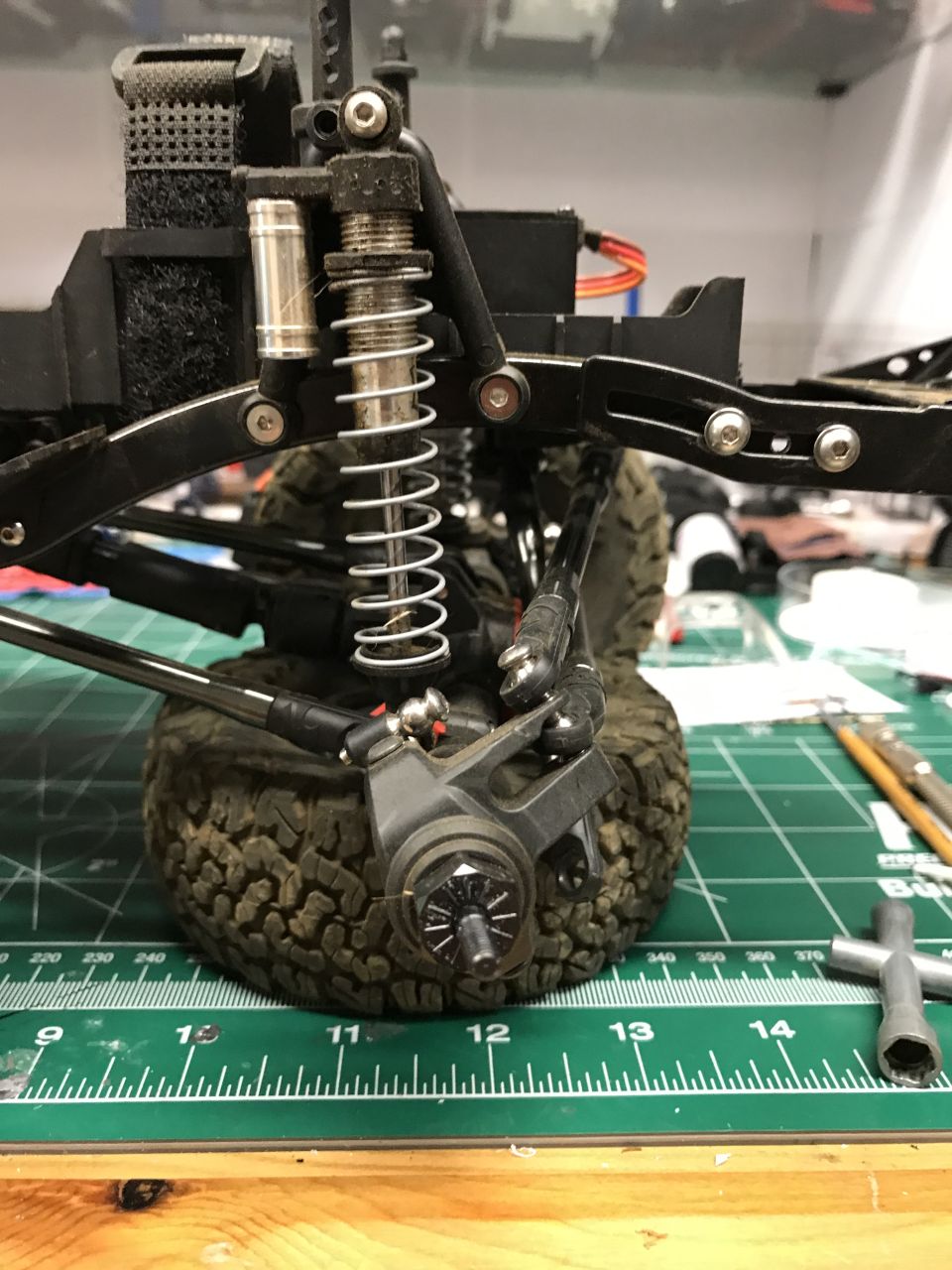 RC car suspension assembly with shock absorber, linkage, and wheel hub on a cutting mat