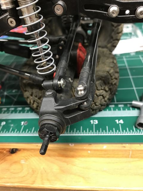1989 Ford Bronco - This is a close-up view of a part of an RC car's suspension system, resting on a cutting mat.