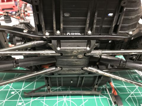 1989 Ford Bronco - The underside of an RC car chassis, with the "Axial" logo clearly visible on the frame.