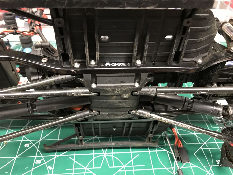 Underside of an RC car chassis showing suspension links and drivetrain components. Axial logo visible