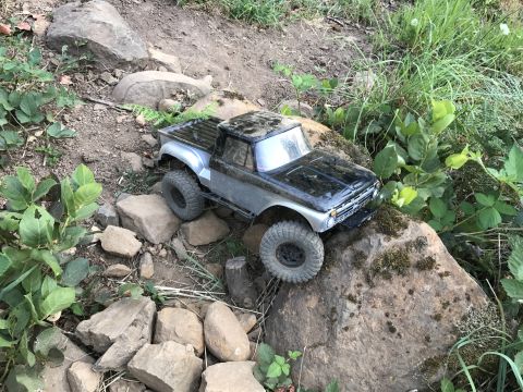 1989 Ford Bronco - A remote-controlled truck navigates a challenging rocky path outdoors.