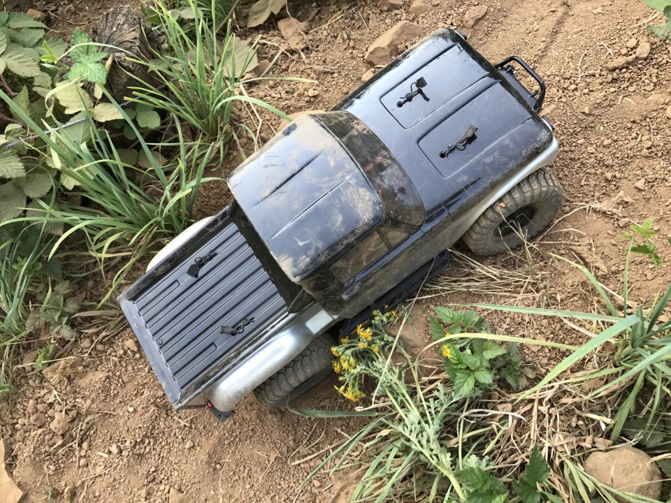 Black toy truck with off-road tires on dirt and grass