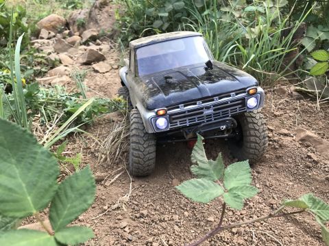 1989 Ford Bronco - A toy truck navigates a rocky, outdoor terrain with green foliage.