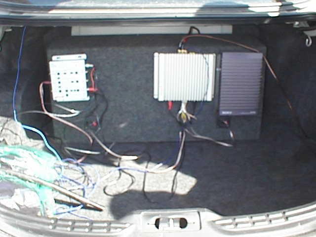 Car trunk with a subwoofer box, amplifier, and wiring. A Sony amplifier is visible