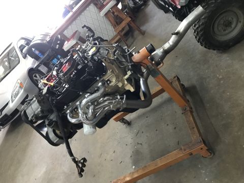 1990 Ford Bronco - Engine on an engine stand, likely a V8, with custom headers and wiring harness.