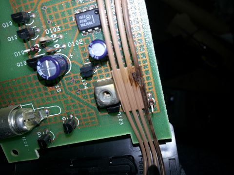 1994 Ford Bronco - Close-up of a burned electronic circuit board with wires and components. Text '1002780' visible on a chip.