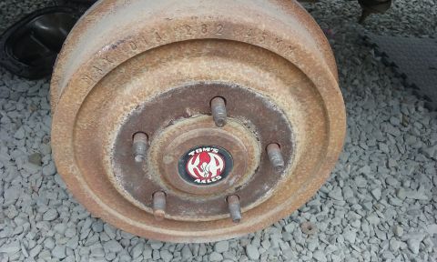 1995 Ford Bronco - A close-up view of a heavily rusted brake drum, identified by a "Tom's Axles" logo and stamped markings.