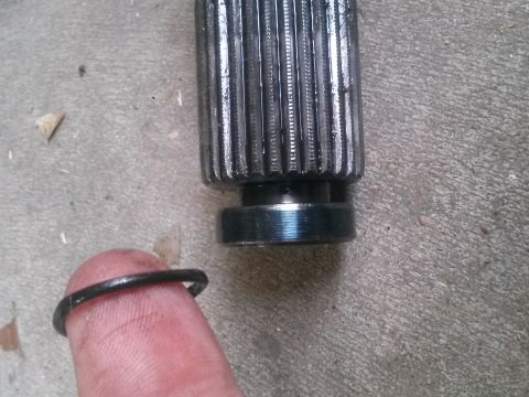 1996 Ford Bronco - A close-up shows a splined shaft and a retaining ring held on a finger, resting on a concrete surface.