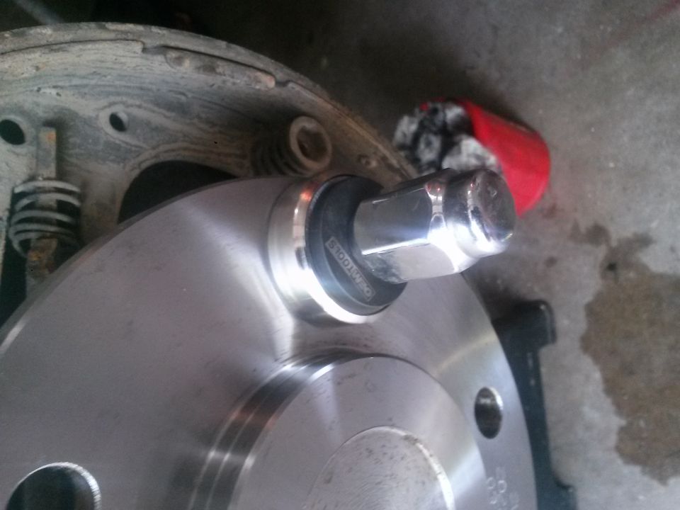 Wheel hub with lug nut and brake drum assembly. A red rag is visible in the background