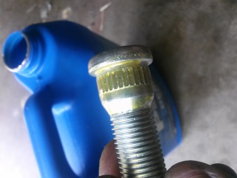 1996 Ford Bronco - A close-up shows a wheel stud, likely for a vehicle, with yellow grease. A blue plastic container is visible in the background.