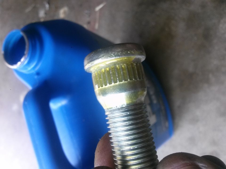 Wheel stud with yellow grease next to a blue plastic container