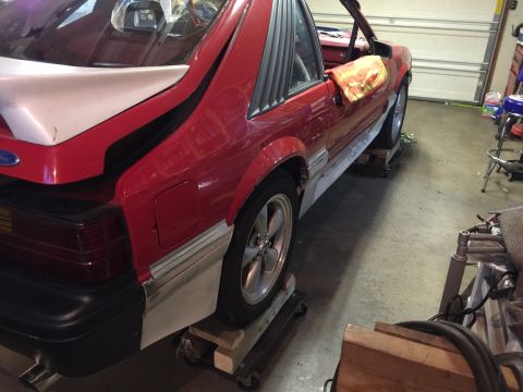 1983 Ford Mustang - Rear view of a red 1983 Ford Mustang coupe with its hood open, resting on dollies.