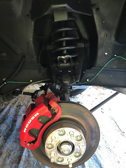 1969 Mercury Cougar - This image shows a close-up of a vehicle's front wheel brake assembly, a red Roush caliper.