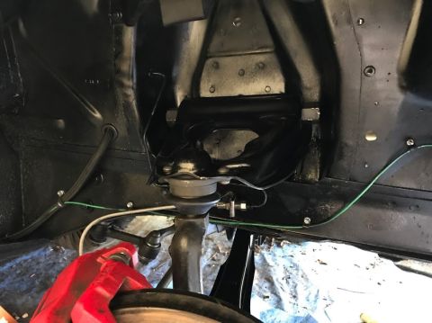 1969 Mercury Cougar - Close-up view of a vehicle's front suspension components, including a red brake caliper.