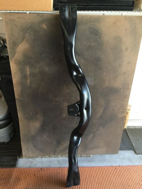 1975 Chevrolet Chevelle - Black metal automotive part with a mounting bracket is displayed against a textured background.