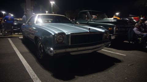 1975 Chevrolet Chevelle - A light blue 1976 Chevrolet Monte Carlo is parked in a lot at night, with a dark green truck behind it.