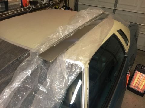 1975 Chevrolet Chevelle - A car is covered in plastic sheeting, with new trim pieces laid on the roof.