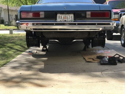 1975 Chevrolet Chevelle - The rear of a blue 1975 Chevrolet Chevelle is raised on jack stands, with tools and cardboard on the ground.