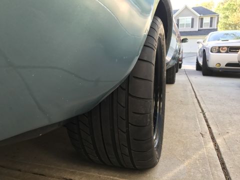 1975 Chevrolet Chevelle - Close-up view of a wide rear tire and fender on a light blue vehicle, with other cars parked nearby.