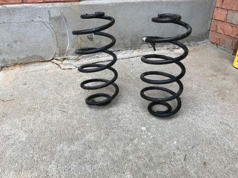 1975 Chevrolet Chevelle - Two black coil springs are shown resting on a concrete surface with a brick ledge in the background.