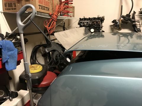1975 Chevrolet Chevelle - A car's hood is open, revealing engine components and other garage items stored nearby.