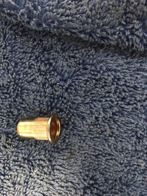 1975 Chevrolet Chevelle - A single brass rivet nut is shown against a textured blue background.