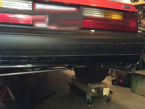 1983 Ford Mustang - The rear of a red 1983 Ford Mustang is shown, with the bumper and exhaust system visible.