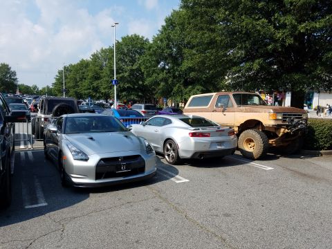 1988 Ford Bronco - A lifted Ford Bronco with a flat tire is parked next to other vehicles.
