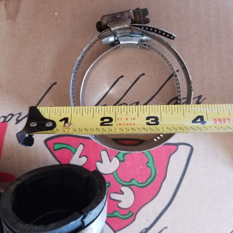 1967 Ford Bronco - A hose clamp is measured with a tape measure, indicating its size.