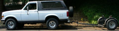 1992 Ford Bronco - A white 1992 Ford Bronco is parked on the side of the road, hitched to a trailer.