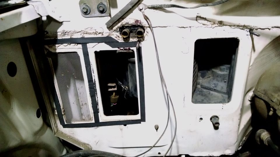 engine bay with openings for components, wires, and hoses visible