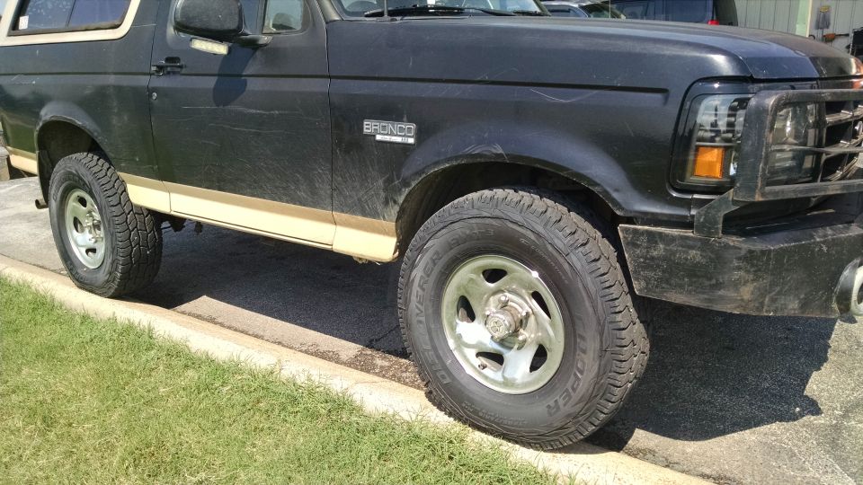 Side view of a black 1990s Ford Bronco with two-tone trim and brush guard, BRONCO badge visible