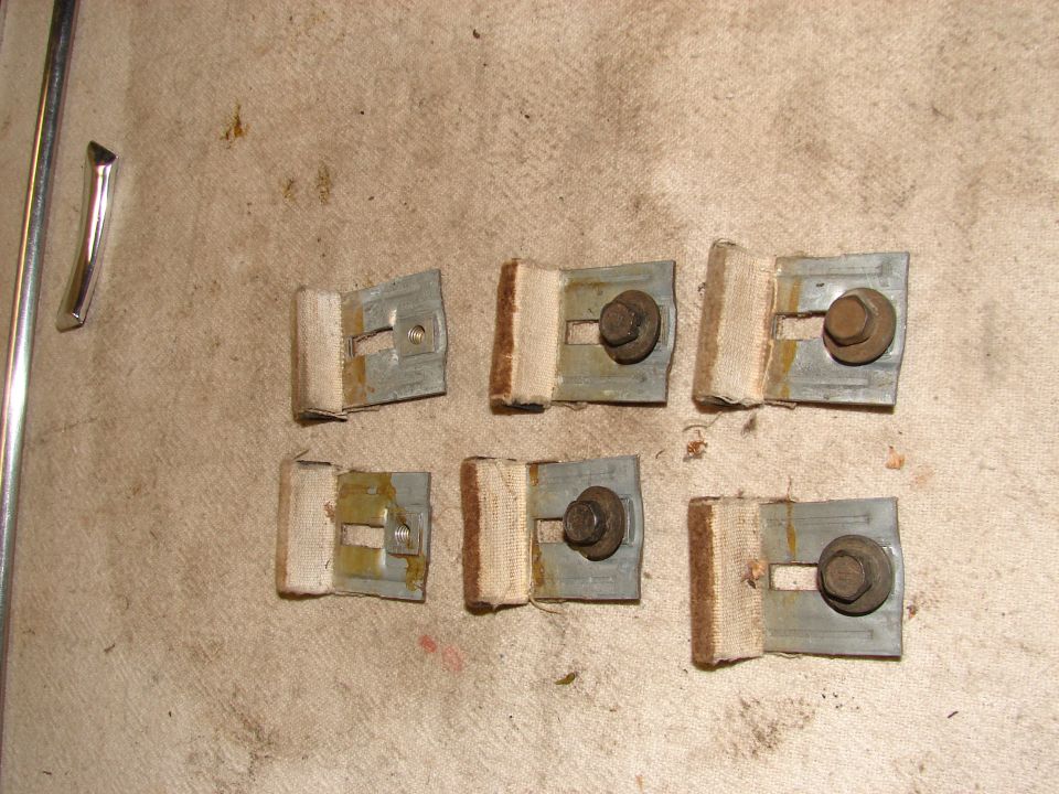 Six metal brackets with fabric and bolts on a textured surface, with chrome trim and a rod.