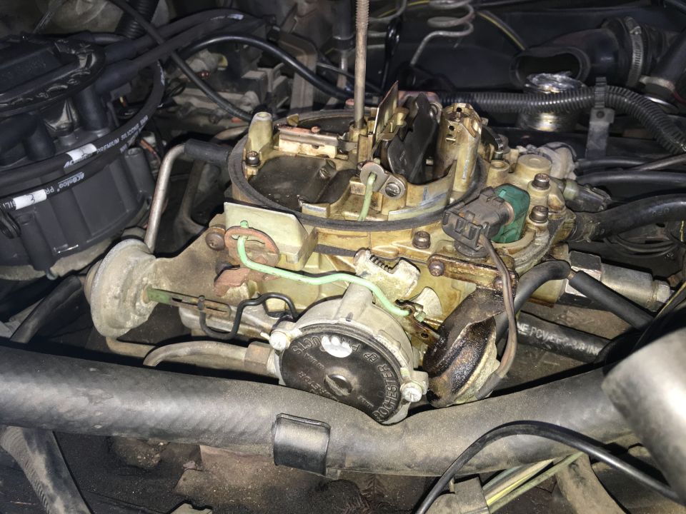 Close-up of a Rochester Quadrajet carburetor on a vehicle engine.