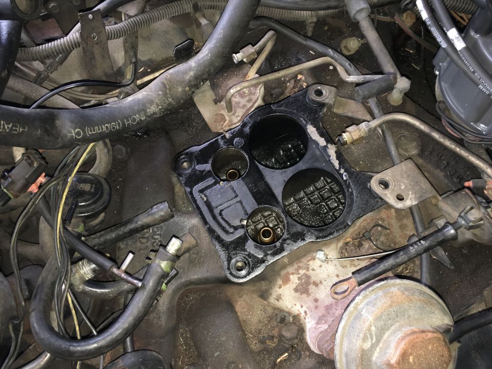 Engine bay with carburetor base plate removed, showing ports and surrounding components.