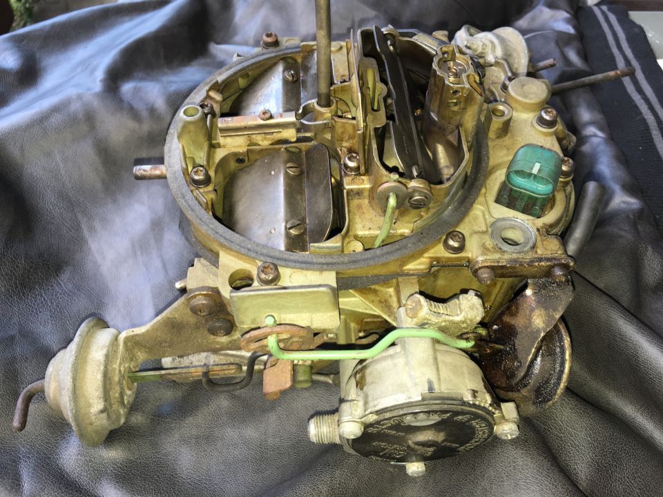 Close-up of a disassembled carburetor on a dark surface.