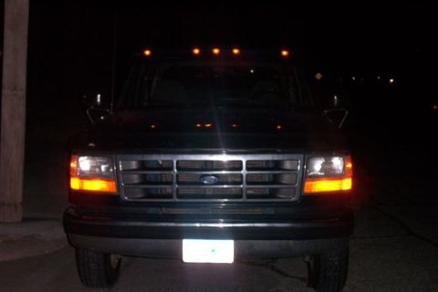 1995 Ford Bronco - Front view of a dark Ford truck at night, with its headlights and amber turn signals illuminated.