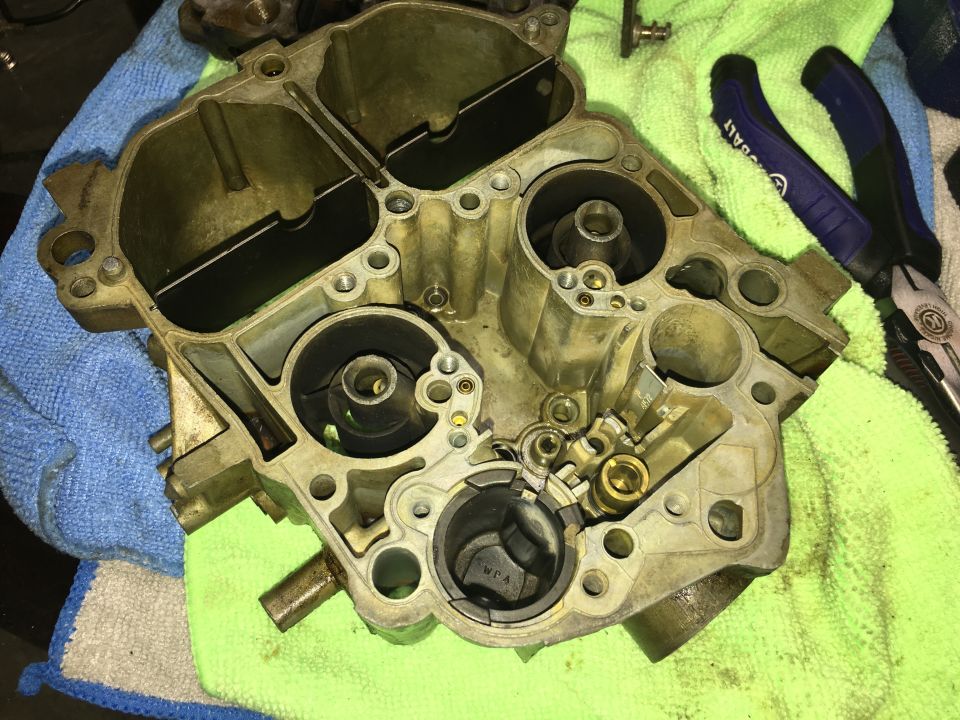 Disassembled carburetor on a cloth with pliers