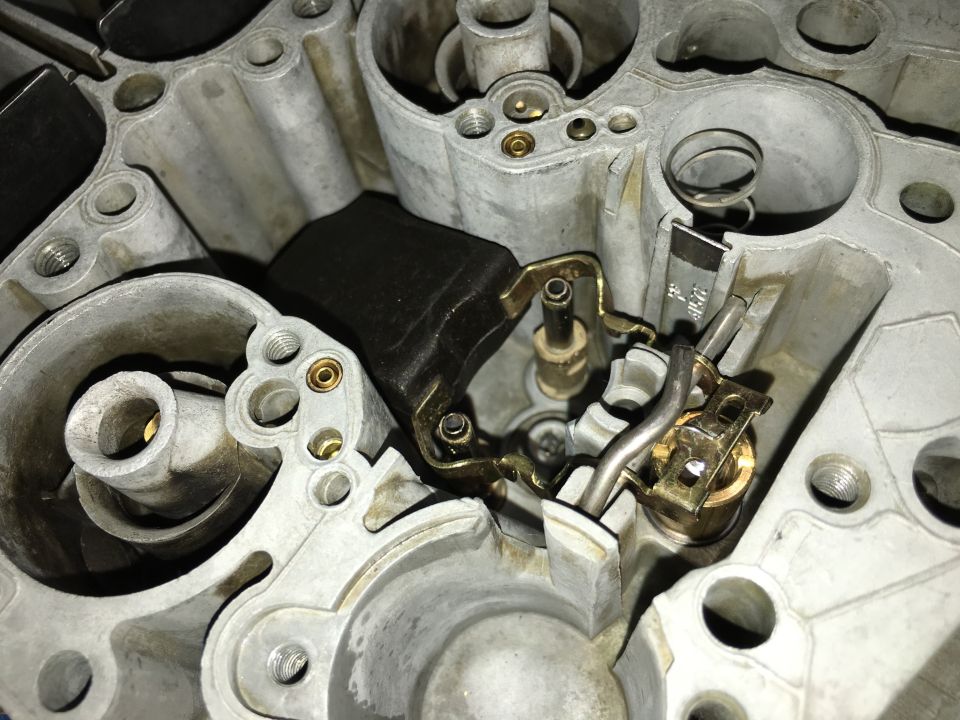 Close-up of carburetor internal components including float and needle valve.