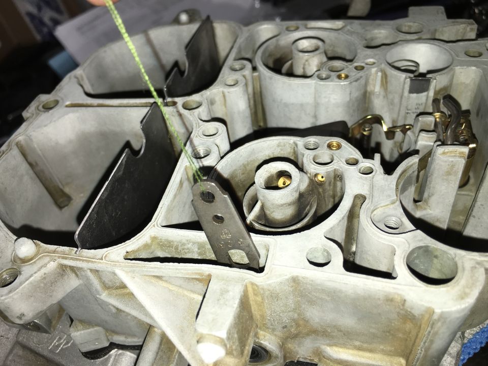 Close-up of carburetor internals with a green string on a lever.