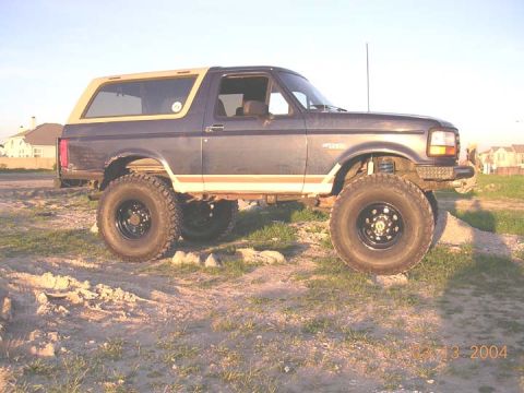 1994 Ford Bronco - This lifted 1994 Ford Bronco features a two-tone paint scheme with a dark blue body and a tan removable top.
