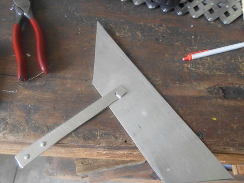 1992 Ford Bronco - A metal triangle ruler with an adjustable arm is positioned on a wooden workbench. A pair of red-handled pliers and a pen are also visible…