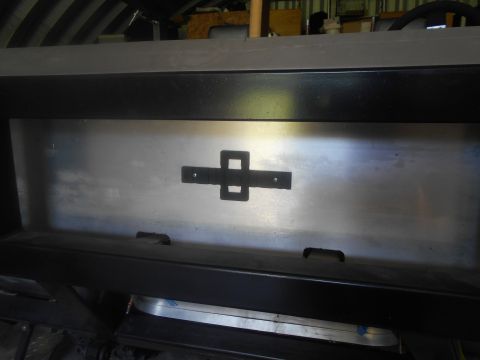 1992 Ford Bronco - A close-up view of a brushed metal panel with a black emblem attached to it. The panel is mounted on a dark-colored vehicle frame.