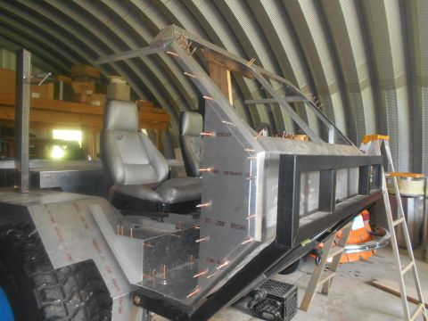 1992 Ford Bronco - A custom-built vehicle frame, likely a Jeep-style buggy, is under construction inside a metal building. The frame features a roll cage stru…