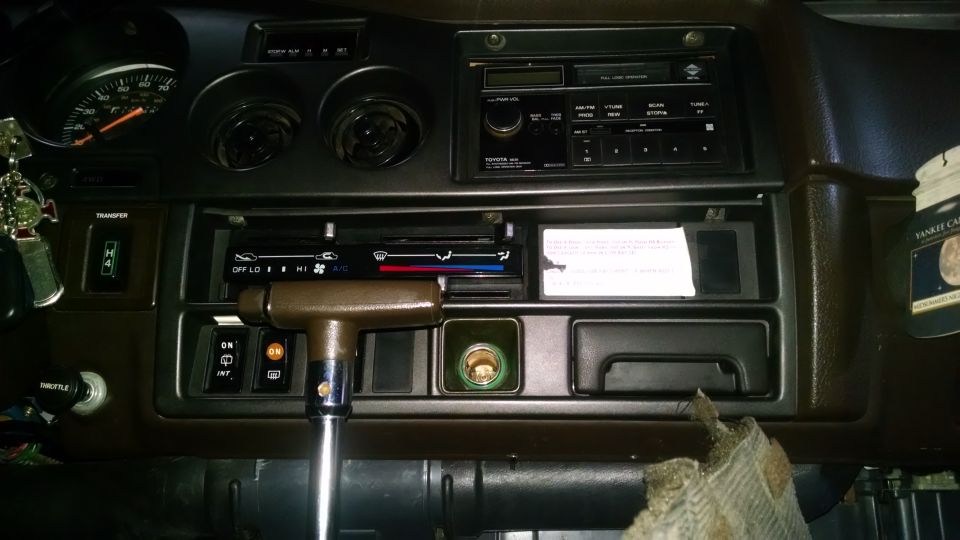 Interior dashboard of a Toyota Land Cruiser with radio, climate controls, and transfer case selector.
