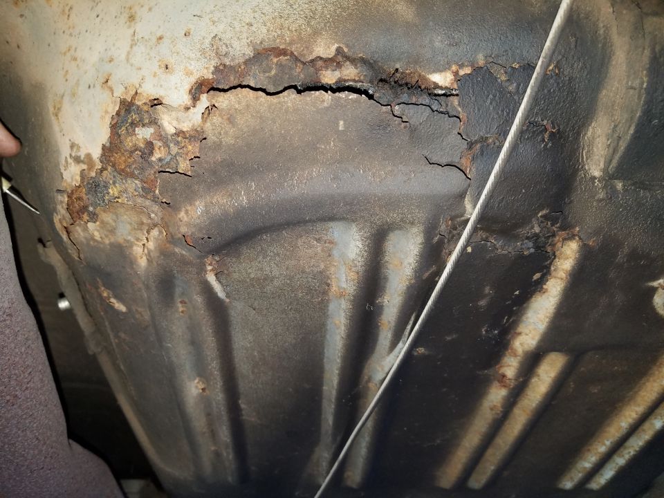 Underside of a vehicle with severe rust and corrosion.