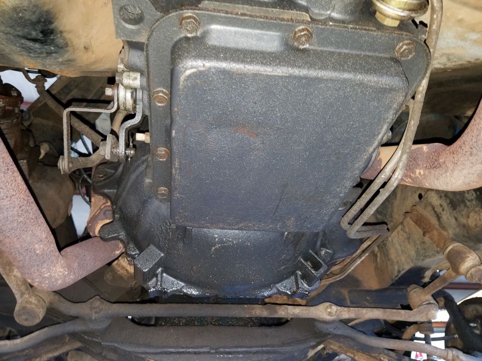 Underside of a vehicle showing the transmission pan and exhaust pipes.